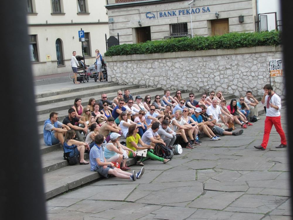 Un gruppo seduto sui gradini ad ascoltare la guida, a Cracovia