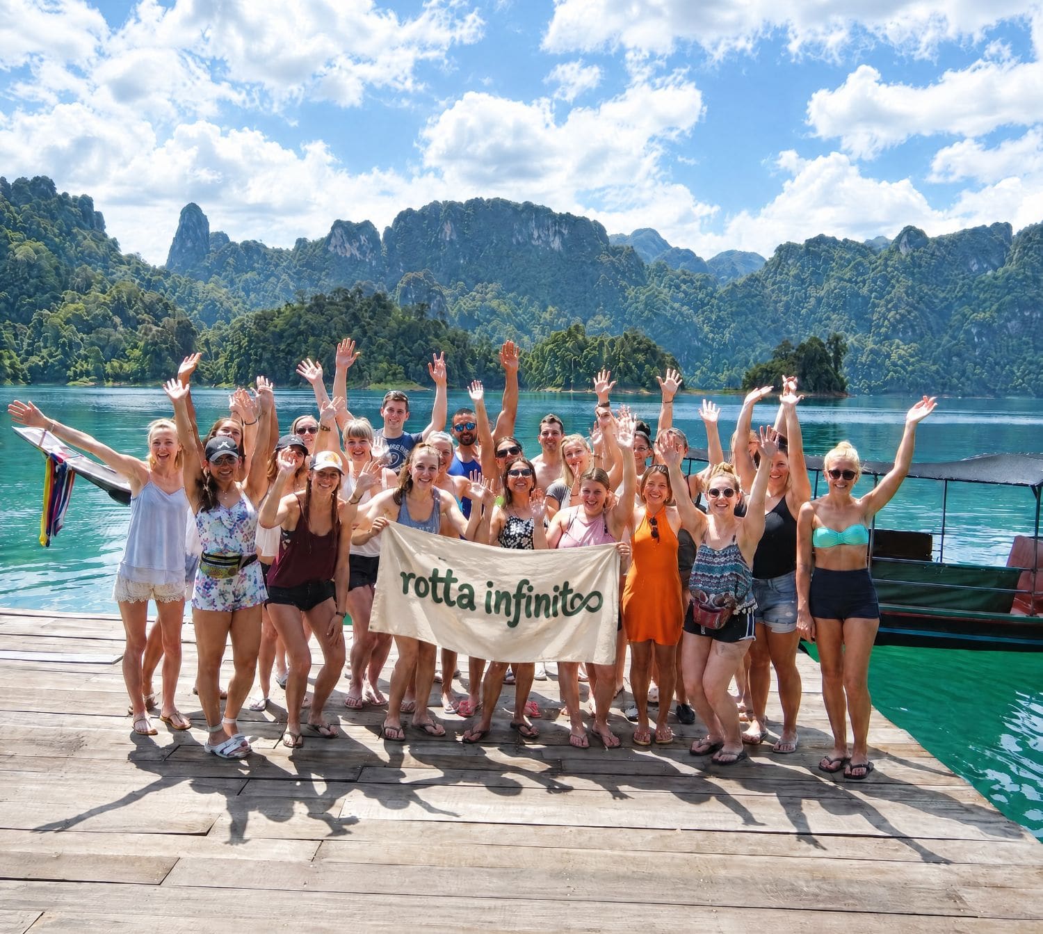 Il gruppo sul pontile al lago di Khao Sok, braccia alzate, acqua turchese