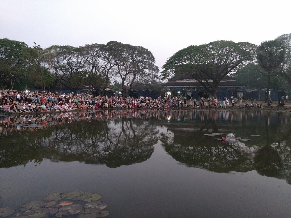 La folla all’alba davanti ad Angkor Wat, riflessa nello stagno